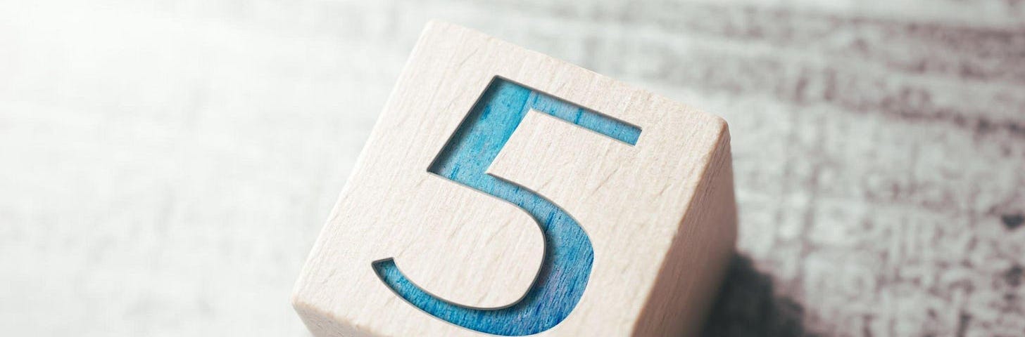 A wooden dice with 5 written on it.