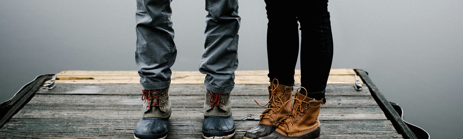 A couple is pictured from the waist down standing on a dock