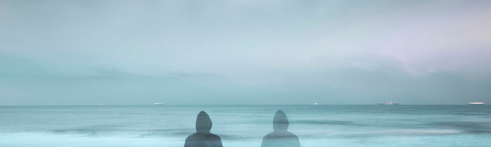 A bluish-grey picture, one person sitting on the left with a mirror shadow on the right, facing the ocean.