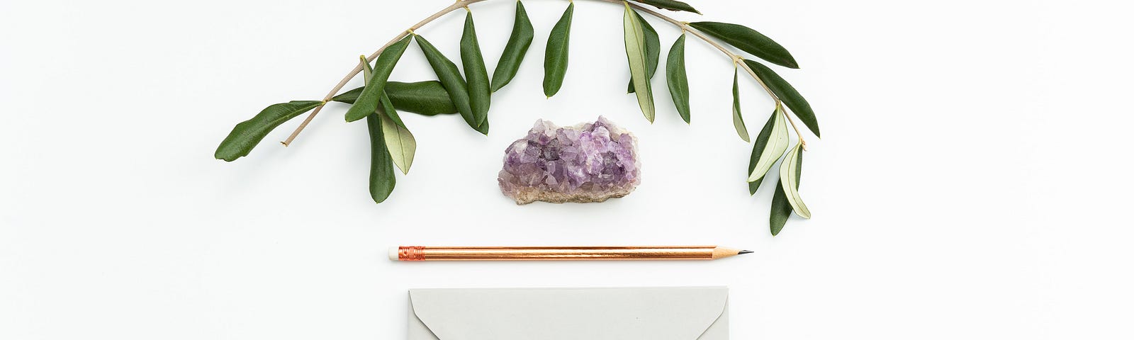 An olive branch, an amethyst stone, a number 2 pencil, and a white envelope.