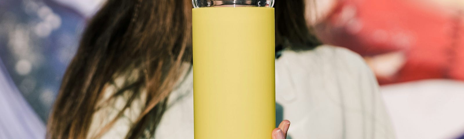 A woman holding a glass bottle filled with with water in her hand.