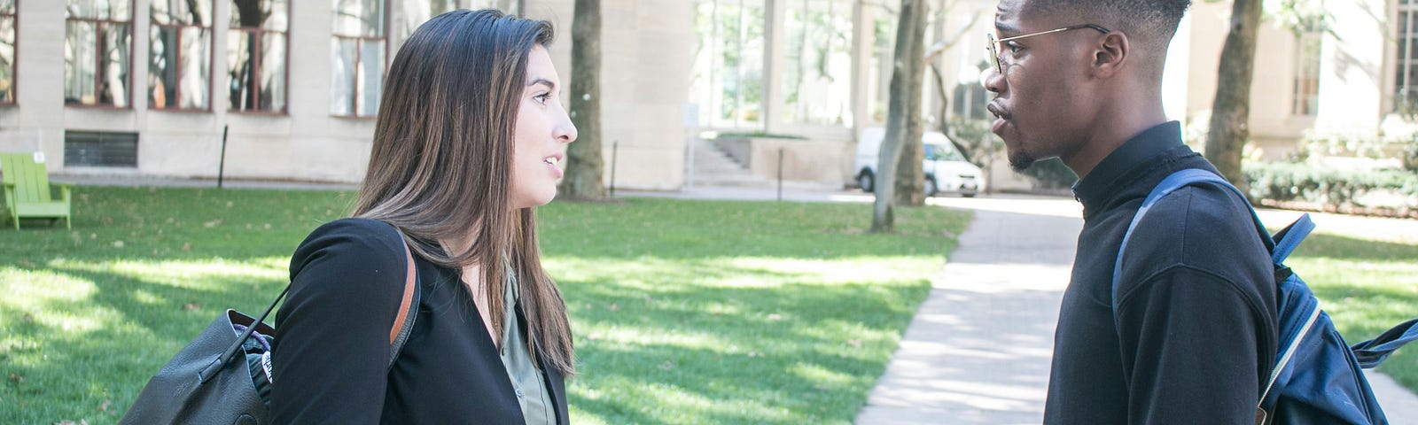 A young man and a young woman speaking to each other.