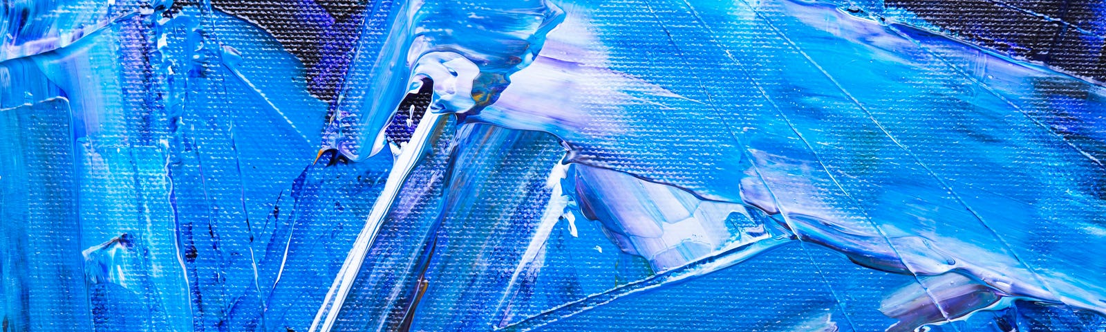 A close up of paint on a canvas with shades of primarily blue, but also white, yellow, and purple. The paint is applied in wide frenzied strokes. The texture of the paint on the canvas is very prominent.