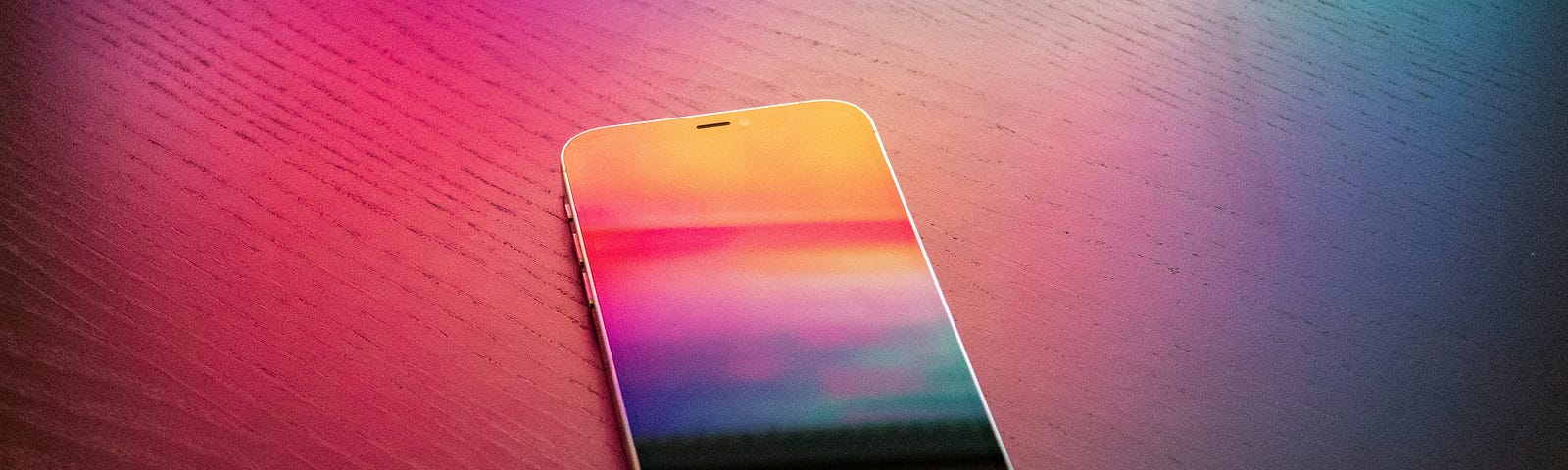 This is a photo of an iphone with a colorful screen, sitting on a background that is alsio colorful, mostly reds and pink.