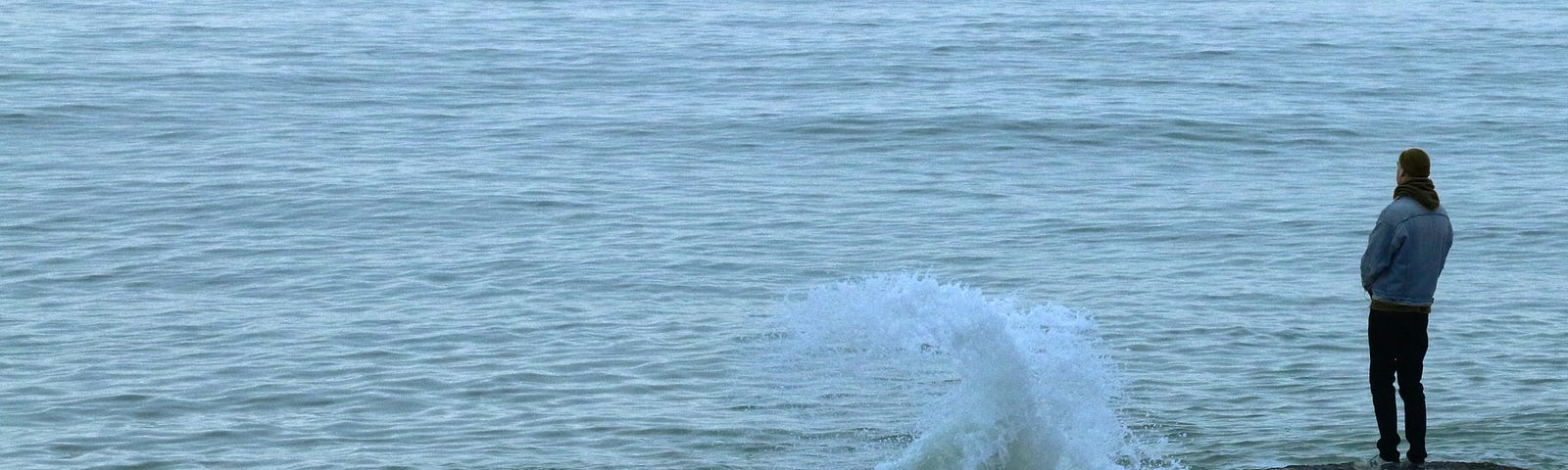 man looking out at the ocean from a rock