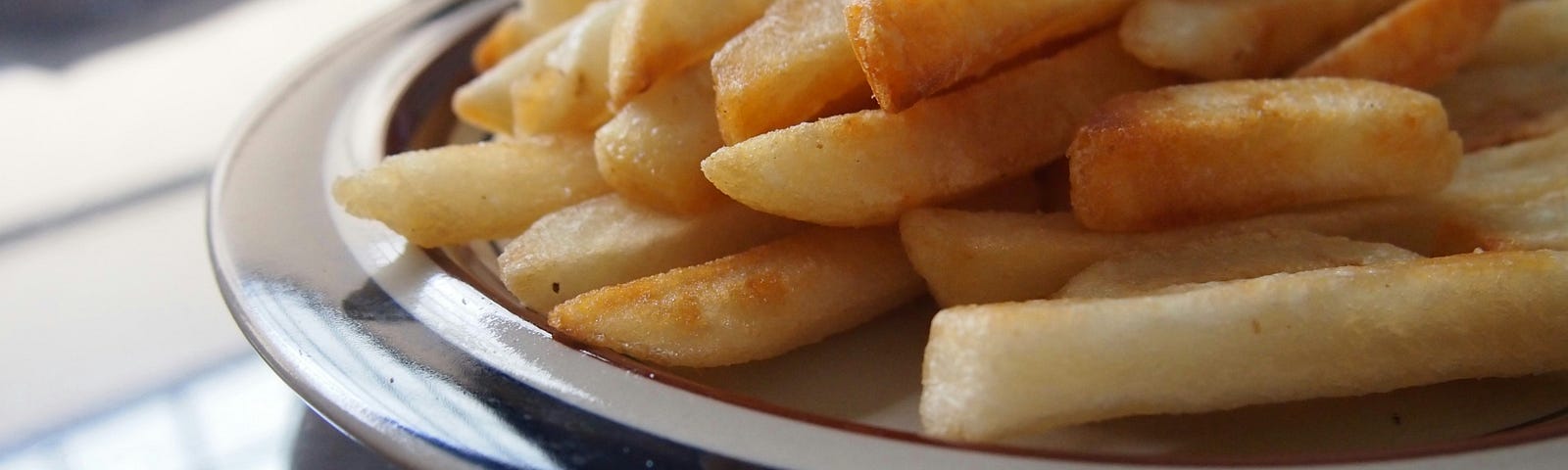 A blue and white plate covered in french fries.