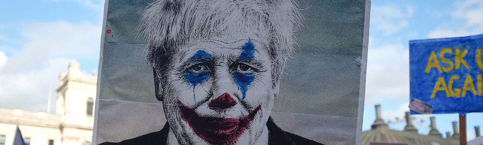 A protestor is carrying a painting of the ex-UK prime minister, Boris Johnson painted as a clown.