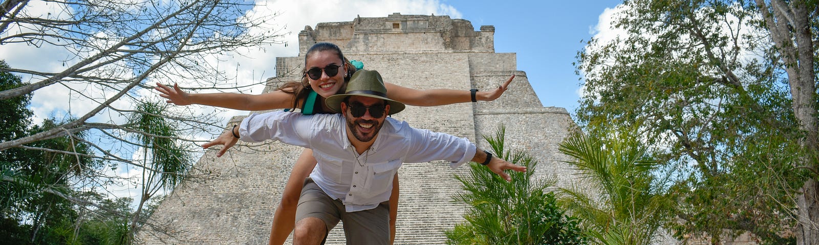 A couple pose for a photograph in front of the spectacular Pyramid of the Magician in Uxmal,  an ancient Maya city of the classical period located in present-day Mexico.