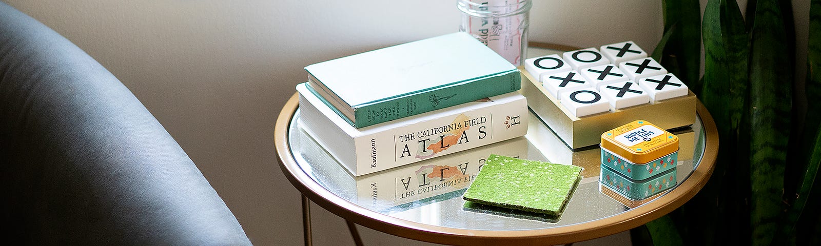 Two thick books (including an atlas), a tic-tac-toe, and assorted objects are on a round table.