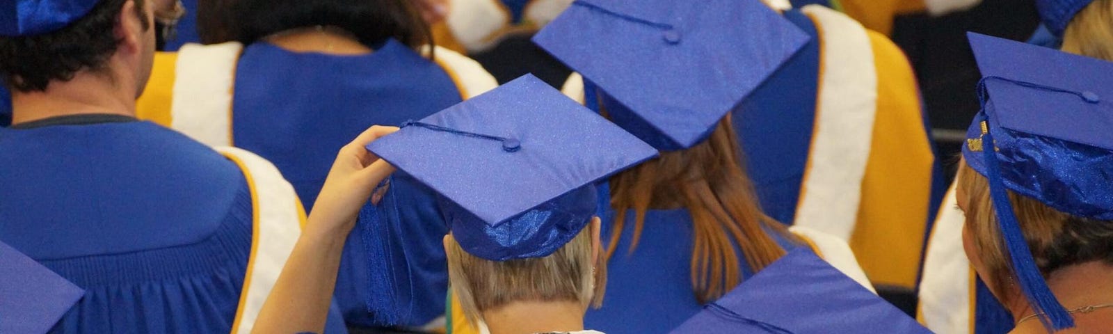 A group of graduates with blue graduation hats.