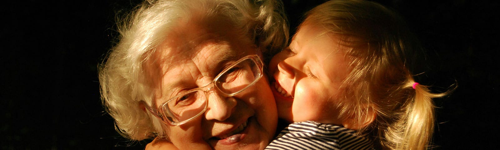 A little girl wildly hugging her grandmother.