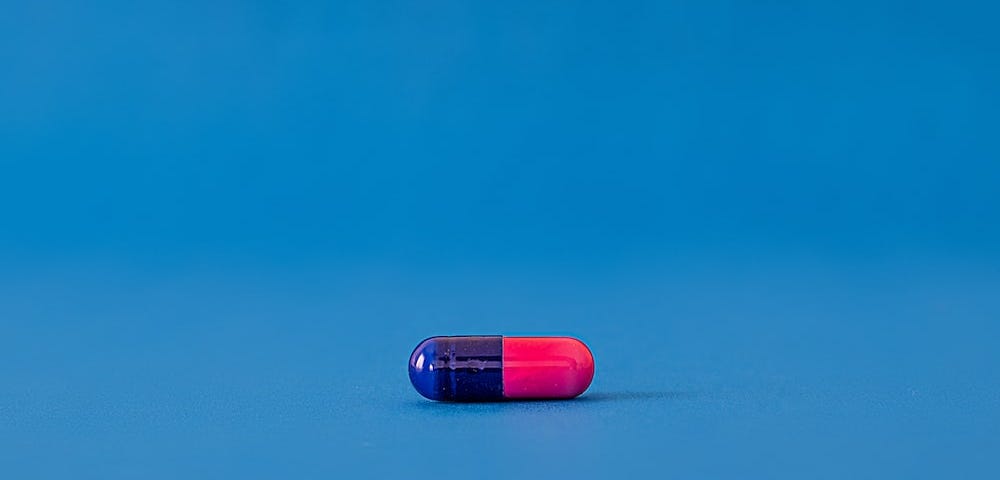 Pink and blue pill on blue background