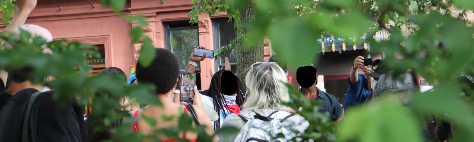 Surrounded by greenery at every angle, a group of activists and protestors raise their fists in Christopher Park, Manhattan.