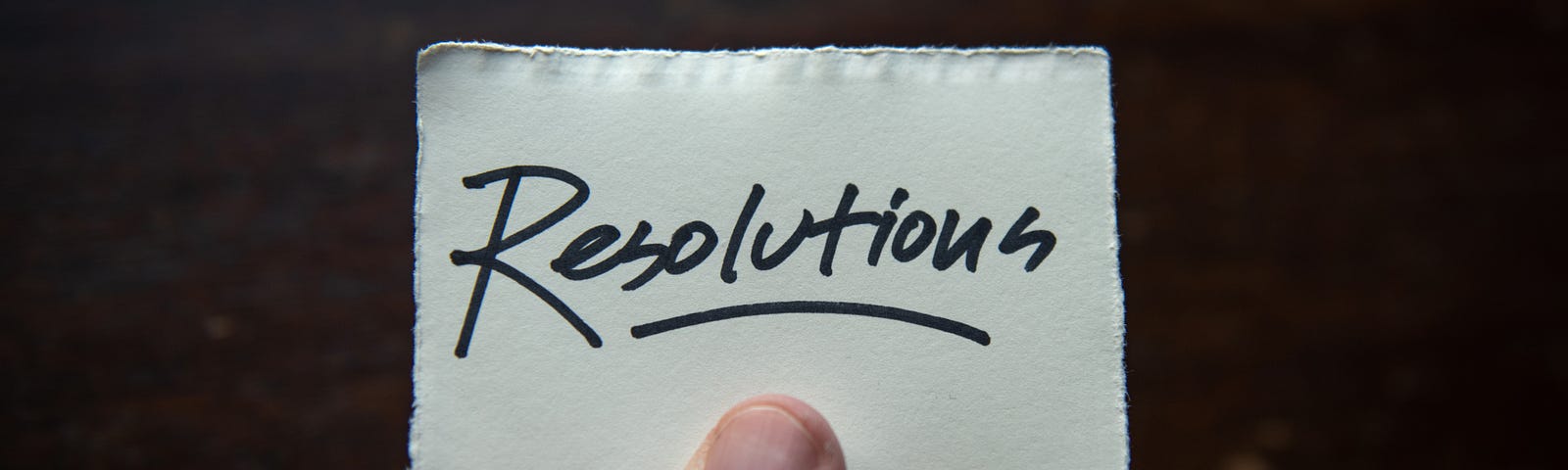 Handwritten “Resolution” held in outstretched fingers. A New Year’s resolution image