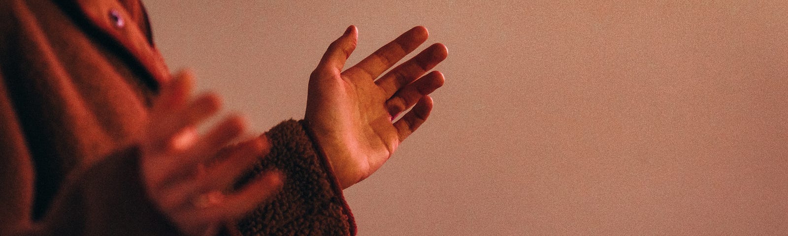 A close-up of someone’s hands raised as if in prayer or worship.