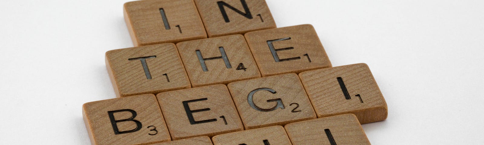 Wooden scrabble pieces arranged to read, “in the beginning”