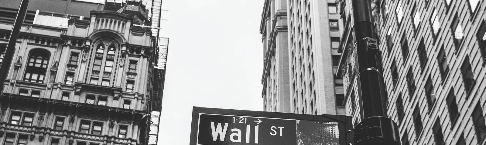 Street sign for Wall St with skyscrapers in the background