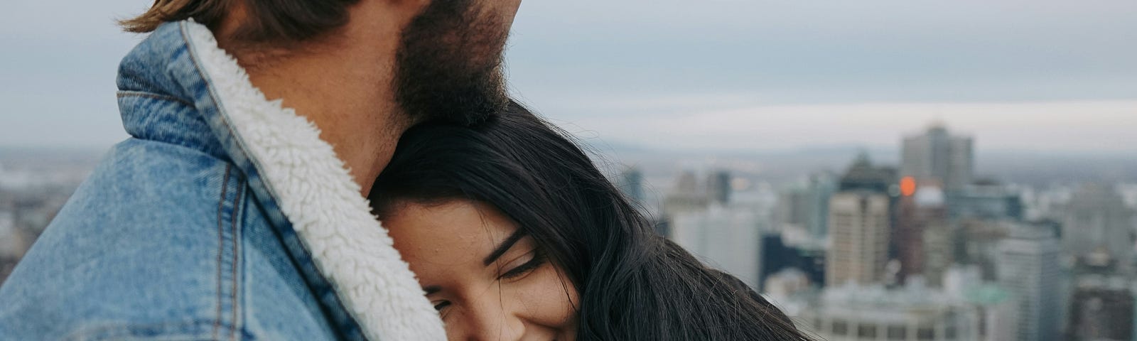 An image of a smiling girl resting her head on a guy’s chest.