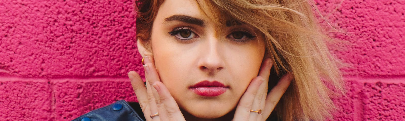 Model sitting against bright pink wall