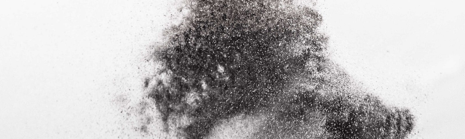 A sandy hand throwing a handful of sand in in the air, in black and white.