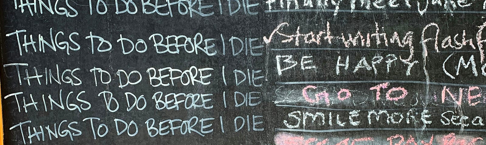 A blackboard with a list of things to do before I die. One is checked off, and some are scribbled over.