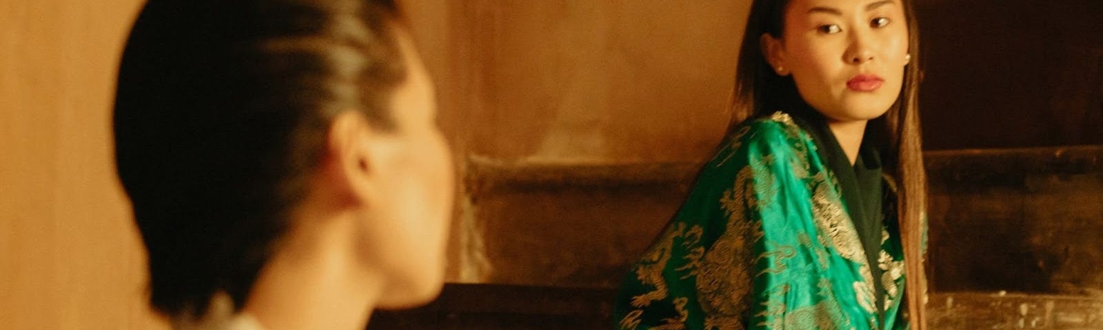 A woman in a green kimono staring at someone