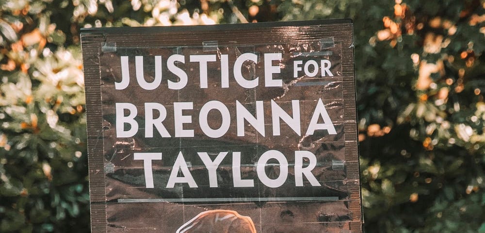 [ID: a placard from a Black Lives Matter protest with Breonna Taylor’s face, which reads “JUSTICE FOR BREONNA TAYLOR.]
