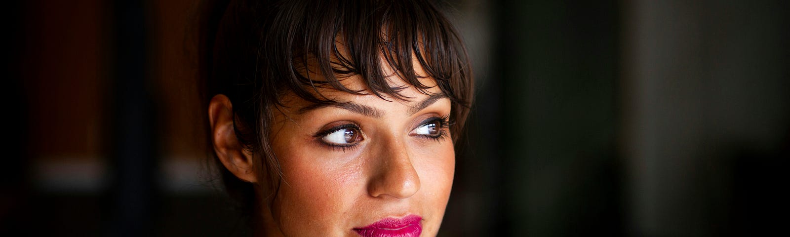 A Brunette woman wearing makeup looking over to the side