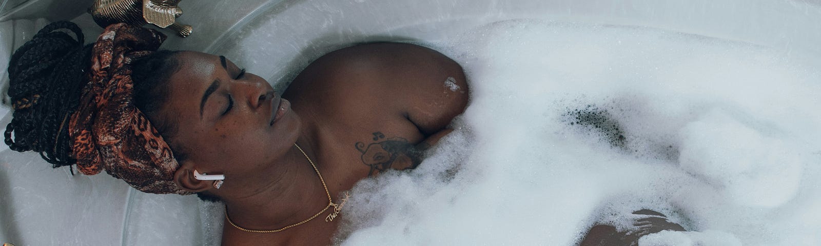 a beautiful black woman relaxes in a bubble bath