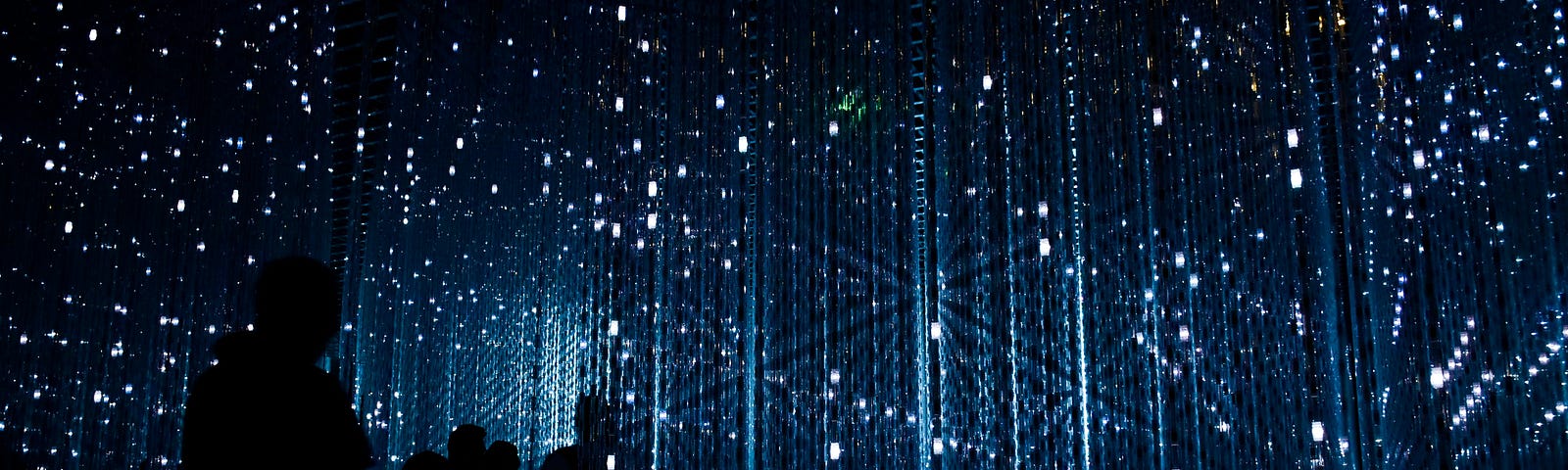 Shadowy figures in a grid of blue-white lights in a dark space
