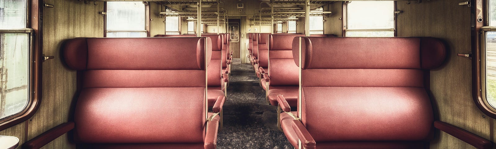 Empty train compartment with pink fabric-covered seats.