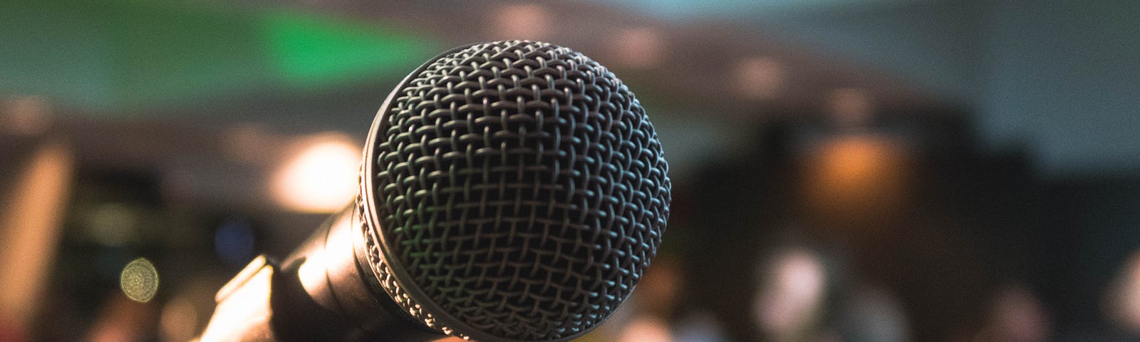 Close up of a microphone with a crowd in the background.