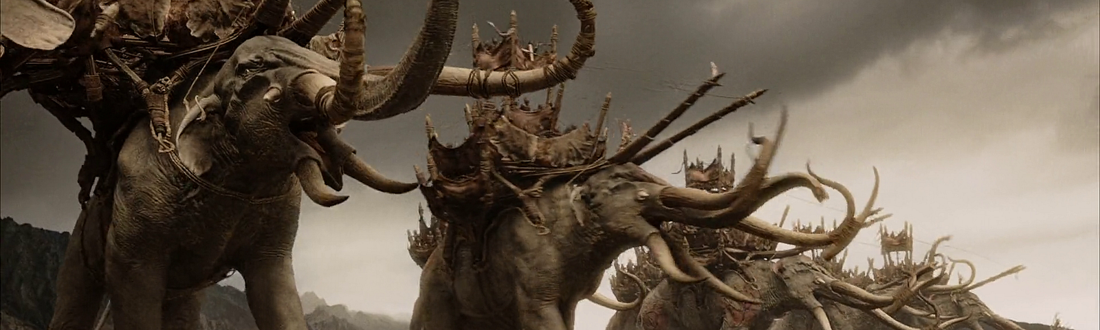 Elefantes gigantes cheios de presas e com cabines no dorso avançam sobre um exército. Cena do filme O Senhor dos Anéis: O Retorno do Rei
