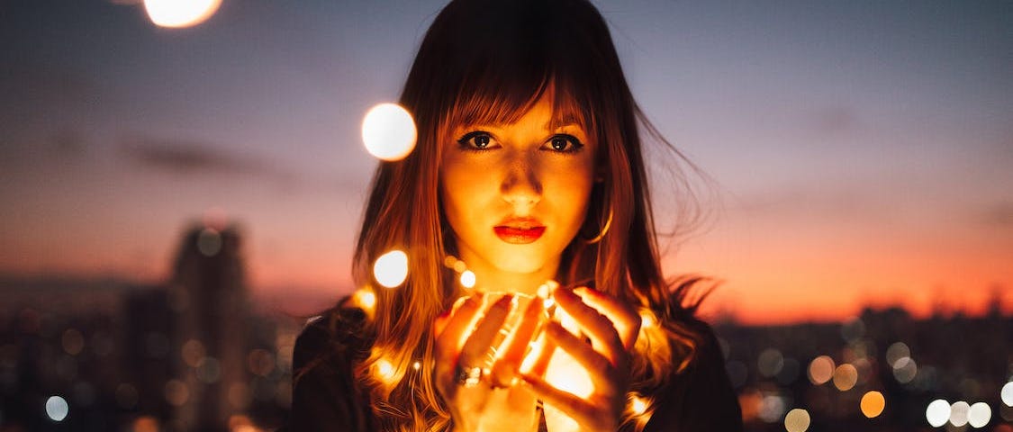 Woman Holding Fairylights on a Rooftop at Night