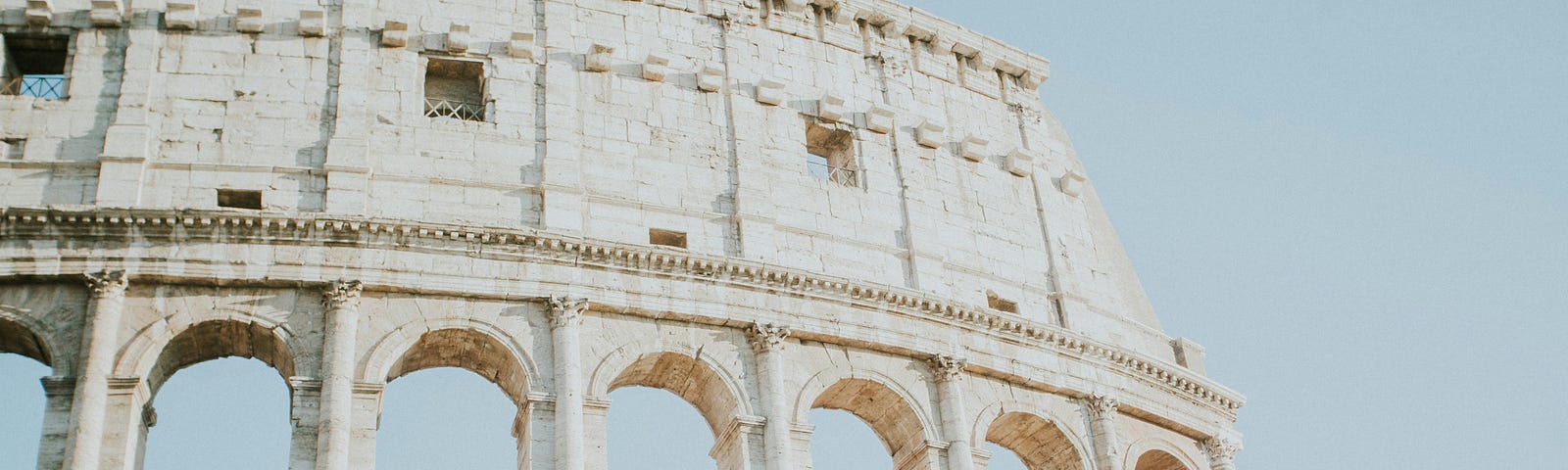 Section of Roman Colosseum against a blue sky.