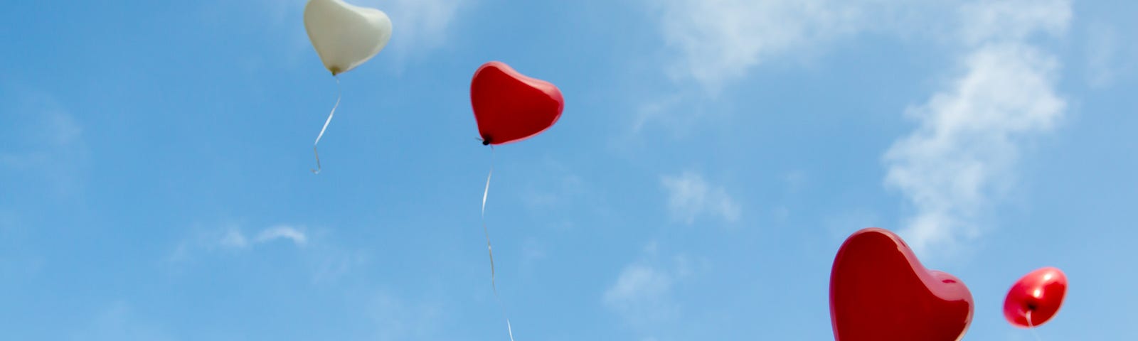 Red and White heart balloons floating away in a clear blue sky. Parenting. Love. Live Lessons
