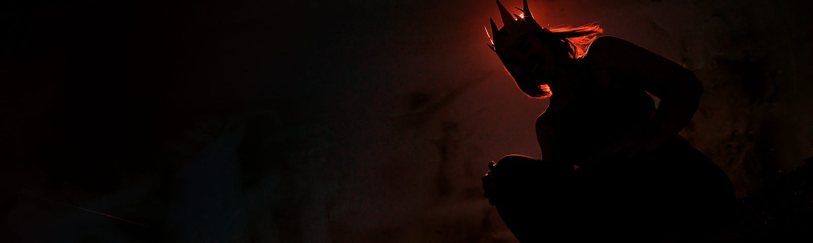 Dark silhouette, backlit with red, wearing a crown