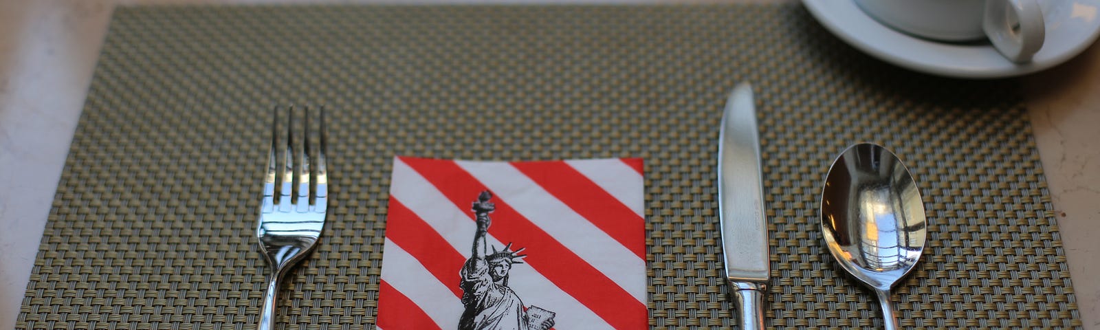 A café detail — fork, knife, and spoon ready for you to order, and in the middle; a napkin with the Statue of Liberty on a starts and stripes background. Very American.