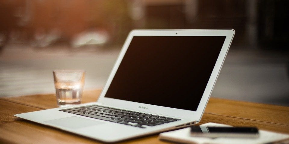 Desk with computer, pen and notebook.