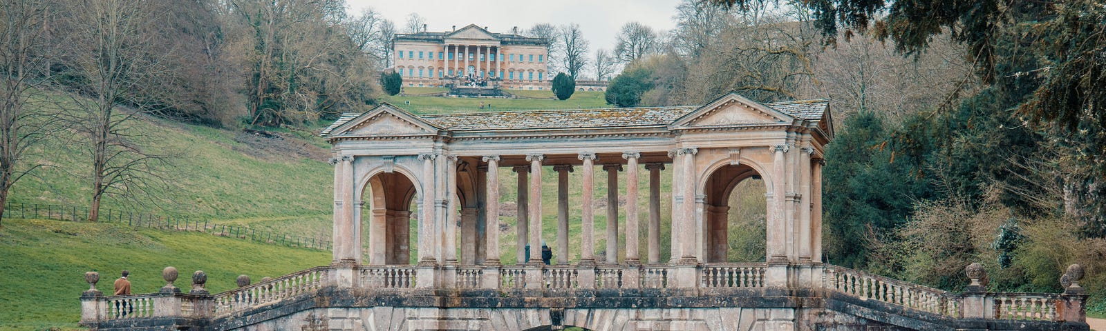 A bridge over a stream, and a grand house in the background, in England