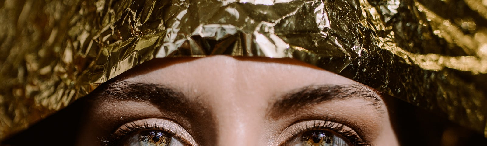 Woman’s eyes looking out of a gold foil background