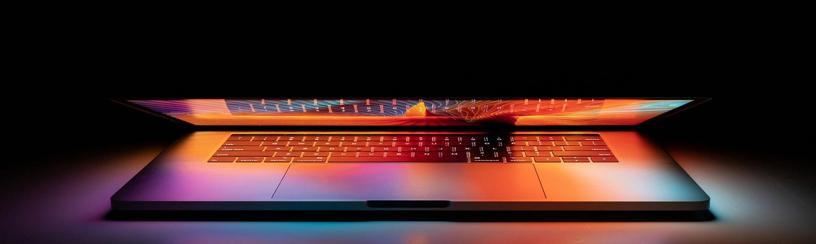 A Lap top lit in red, white and blue colors.