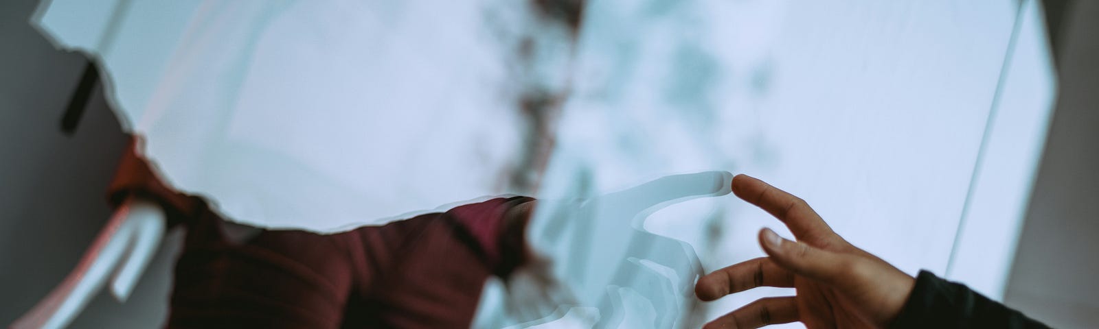 Hand reaching towards its reflection in a glass, symbolizing self-reflection and introspection.