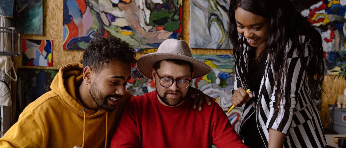 Casually dressed colleagues discussing feedback in front of colourful paintings