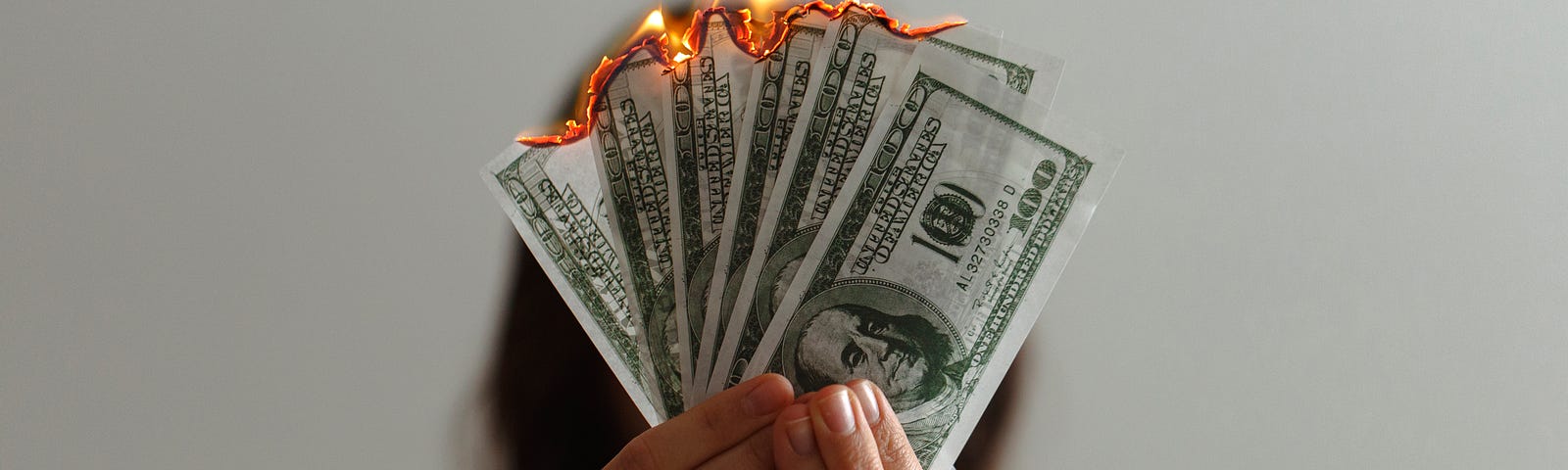 A woman holding a money that is burning on her hands altogether.