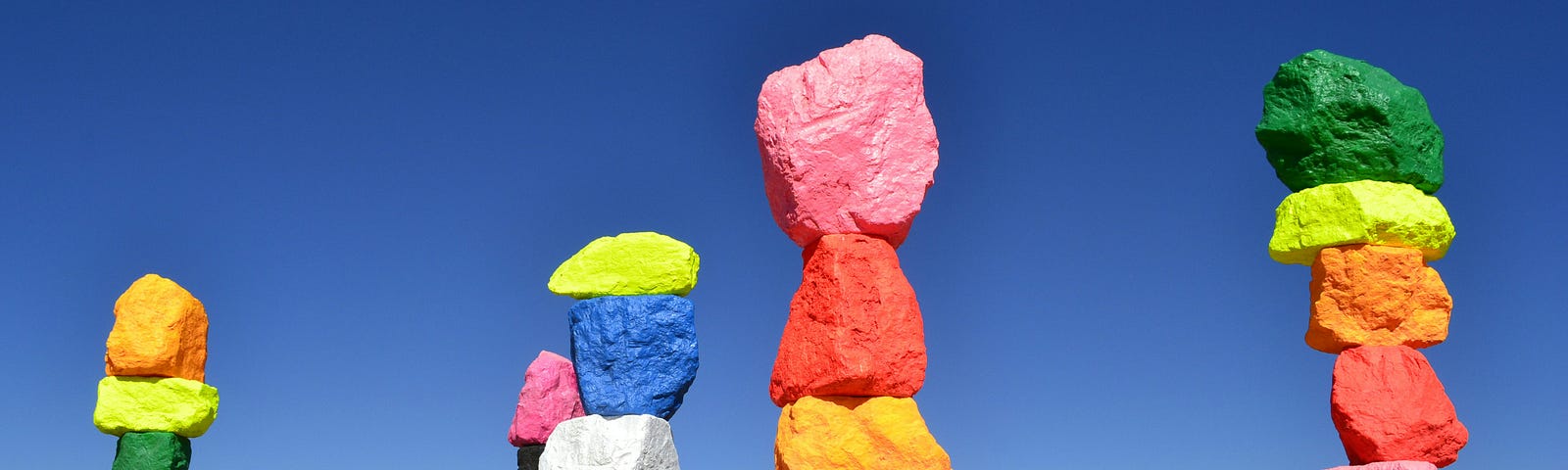 brightly painted rocks stacked up, like pillars, in a desert