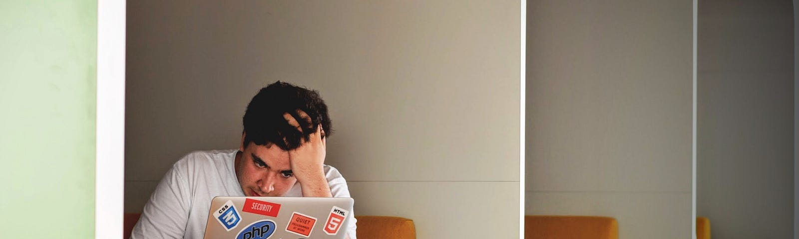 Man sits at a restaurant while anxiously looking at his laptop.