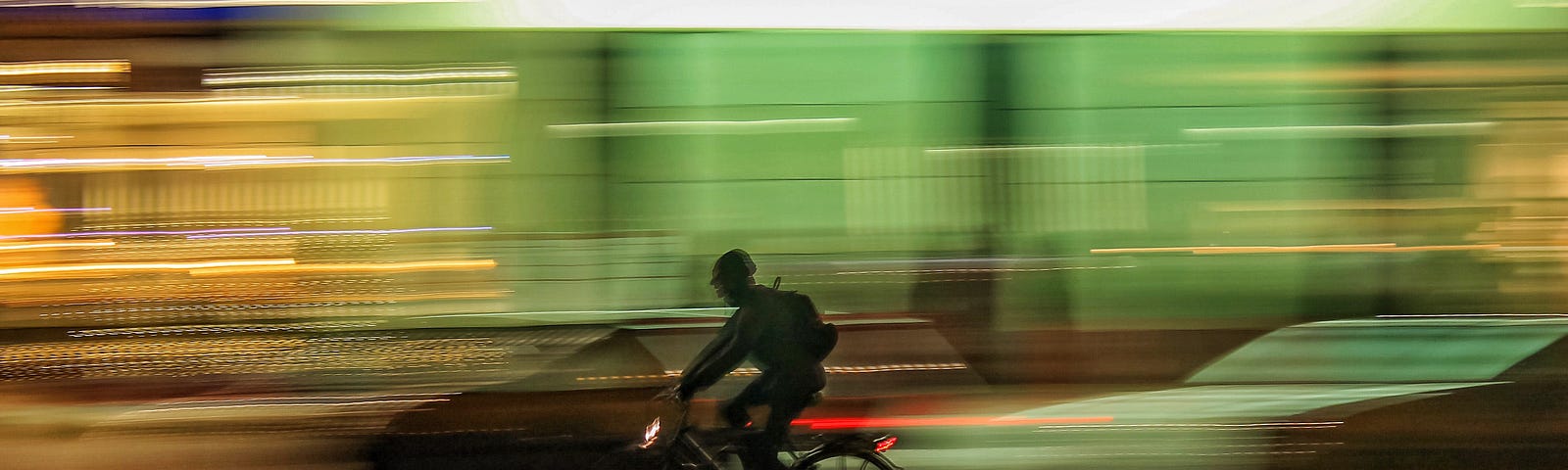 Blurred photo of bicycle rider along a busy night-time street