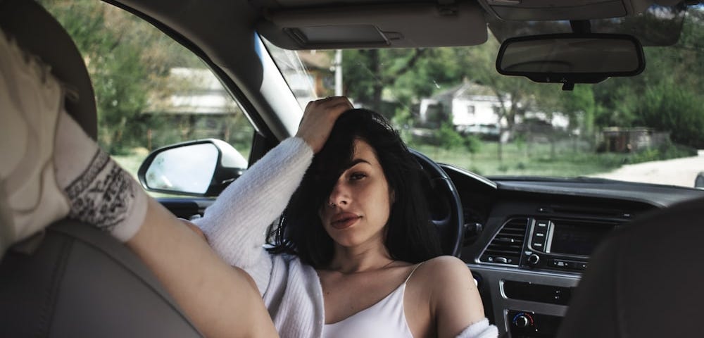 Gorgeous woman resting against the steering wheel inside a car