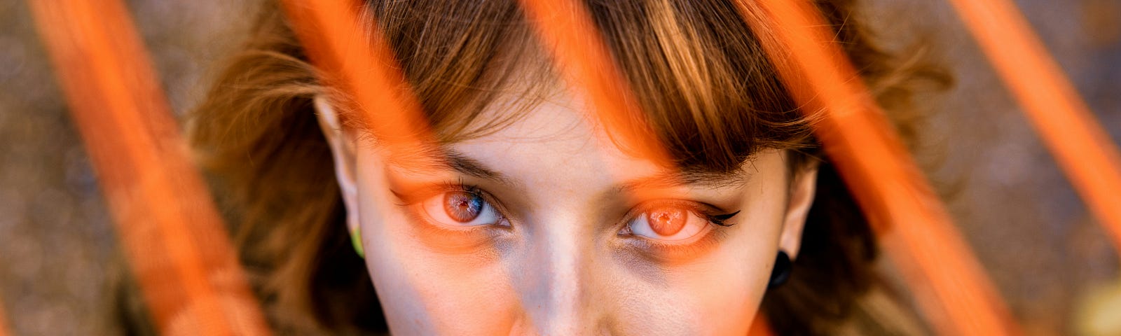 Photo of auburn haired girl’s face with bright orange flashes of light in front of her.